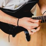 Guitariste jouant un accord de si majeur à la guitare avec un barré sur le manche.