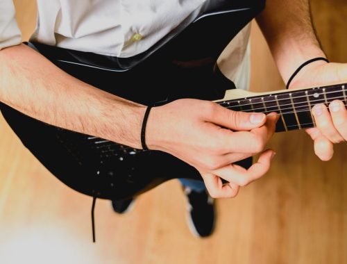 Guitariste jouant un accord de si majeur à la guitare avec un barré sur le manche.