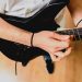 Guitariste jouant un accord de si majeur à la guitare avec un barré sur le manche.
